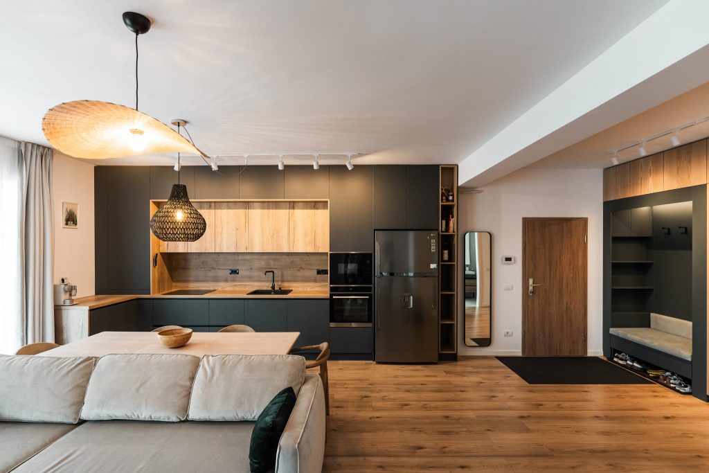 Bucătărie deschisă spre living, cu mobilier verde închis și stejar